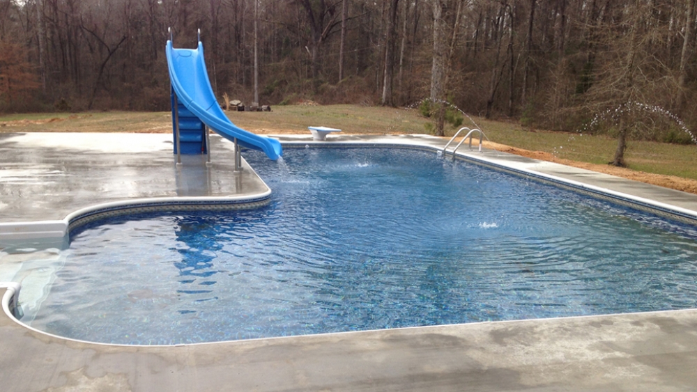 L-shaped swimming pool with a slide and diving board.
